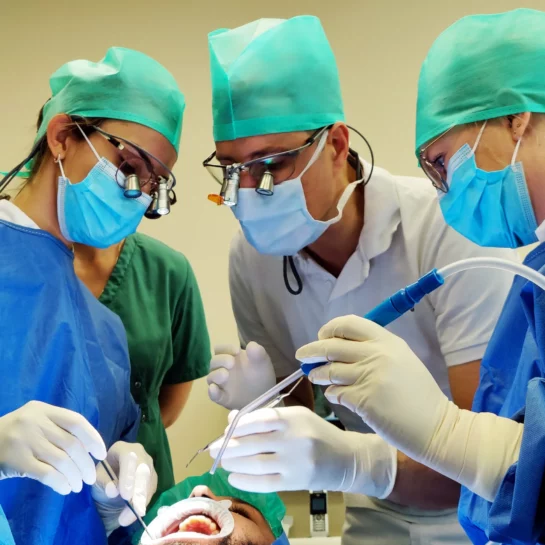 3 implantologen voeren een behandeling uit op een patient